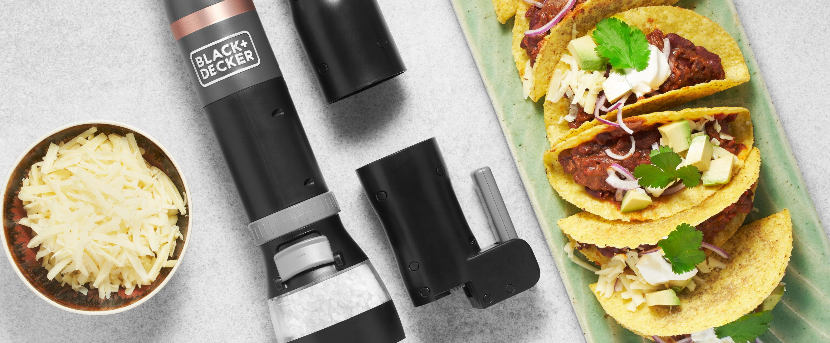 Grey, Black-and-decker kitchen wand with spice grinder, can opener and bottle opener attachments next to chili con carne tacos