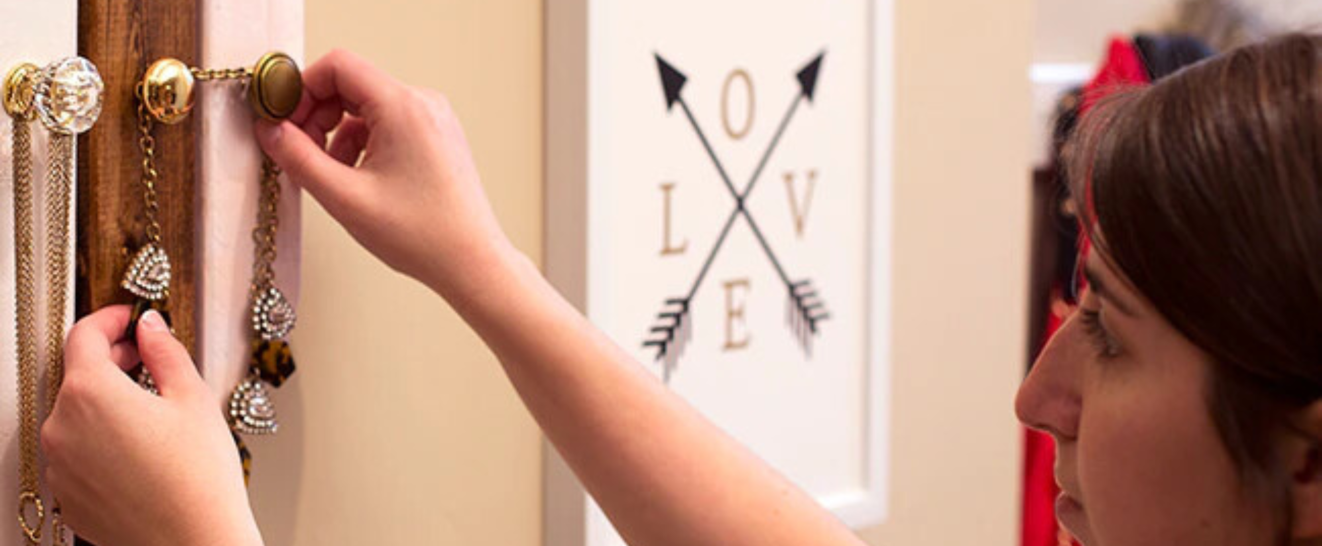Woman hanging jewelry on an on-wall organizer