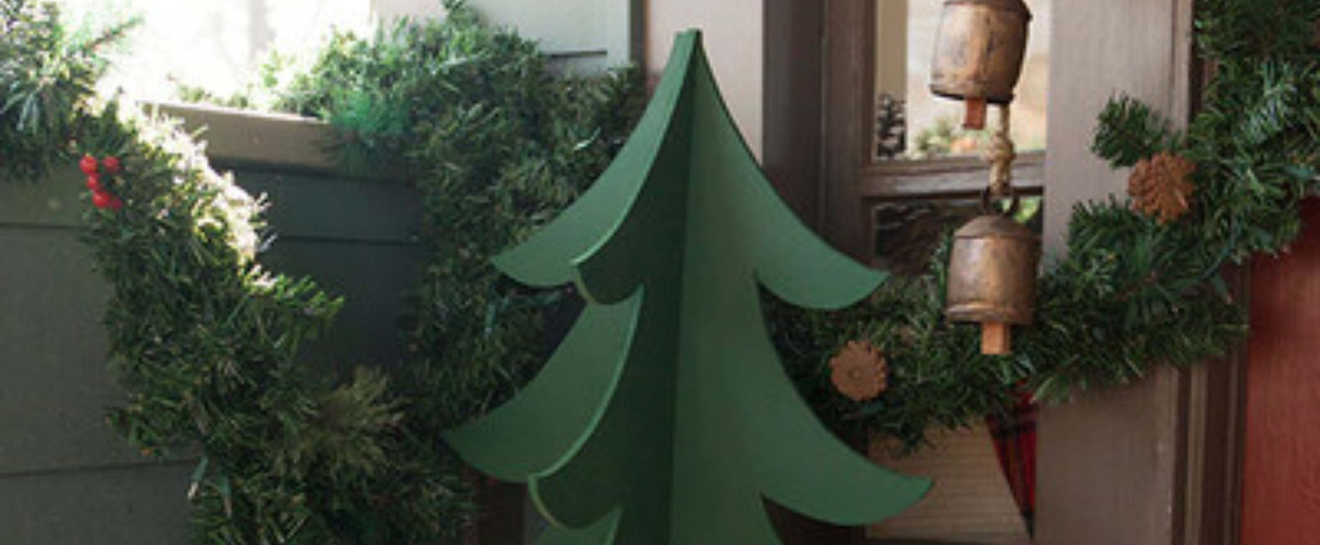 Miniature wooden Christmas tree in corner of room with other Christmas garland and decorations