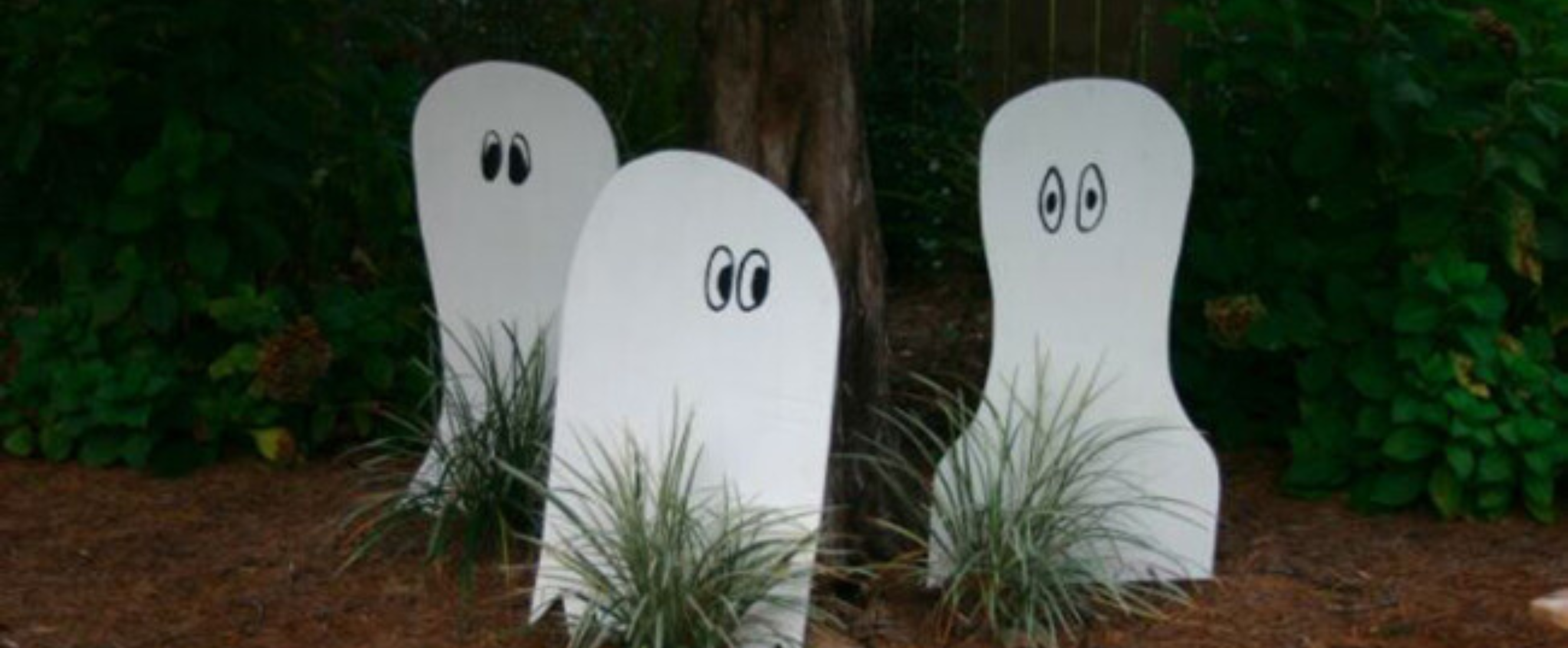 Three wooden ghost decorations in front yard