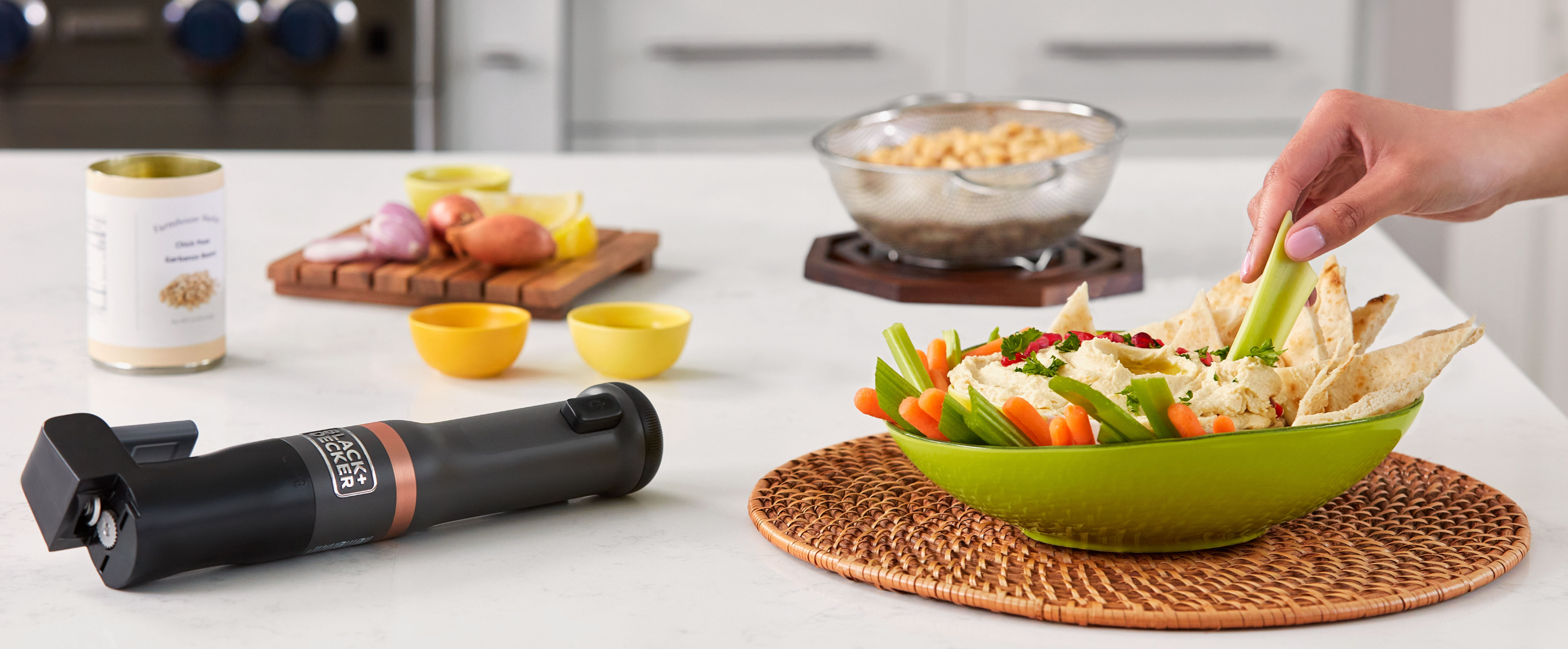 Zoomed in shot of talent dipping celery into prepared hummus, featuring the grey, Black-and-decker kitchen wand can opener