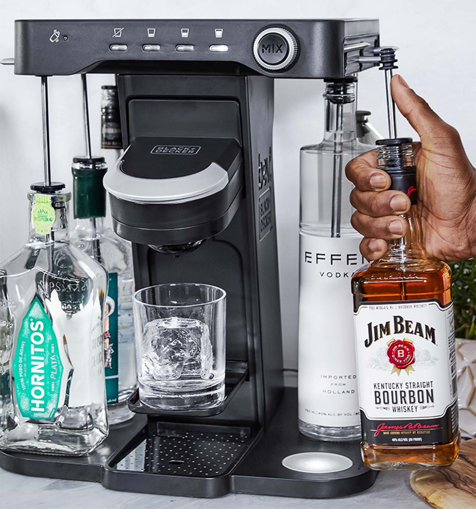 close-up, on the patio, of a man's hand loading a bottle of whiskey into the easy load liquor system on the bev by Black-and-decker™ cocktail maker