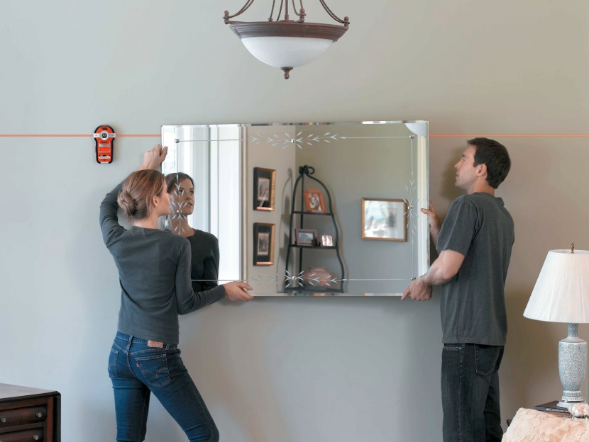 Couple using Black-and-decker laser pointer to hang a mirror