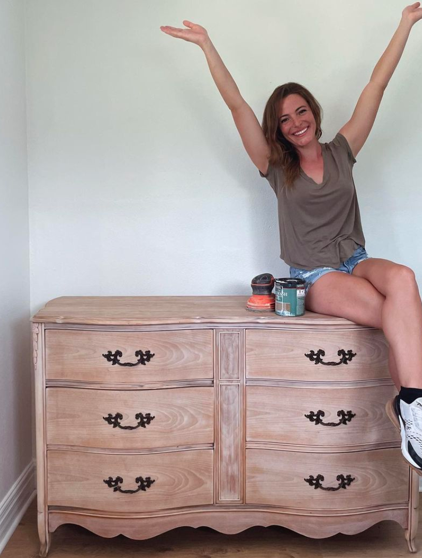 Woman sitting on a sanded dresser with Black-and-decker sander